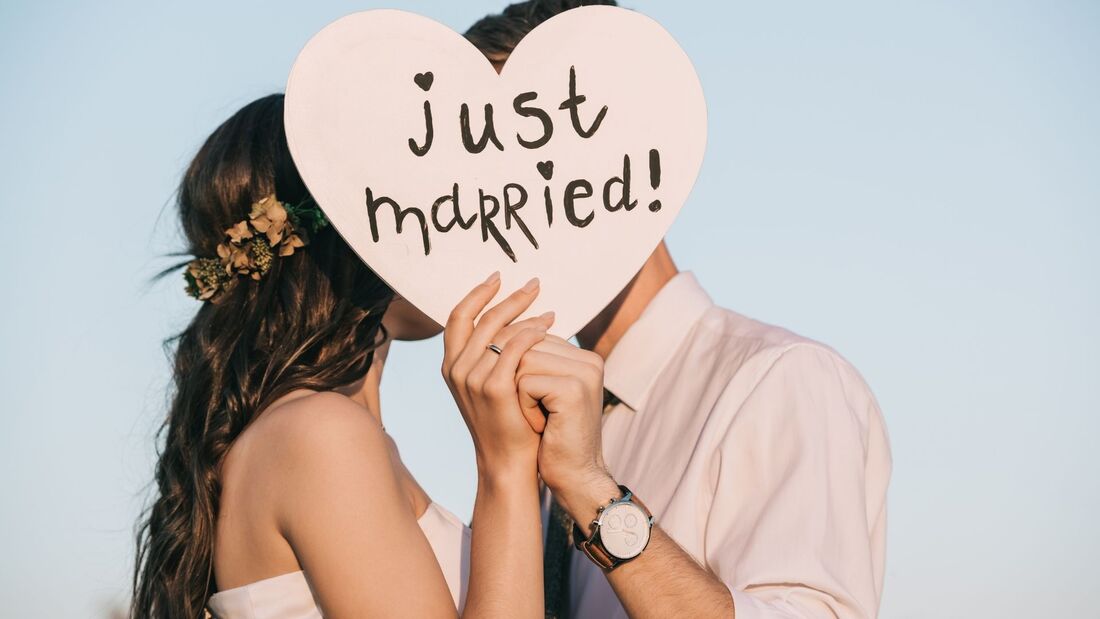Bride and groom kissing behind a Just Married sign